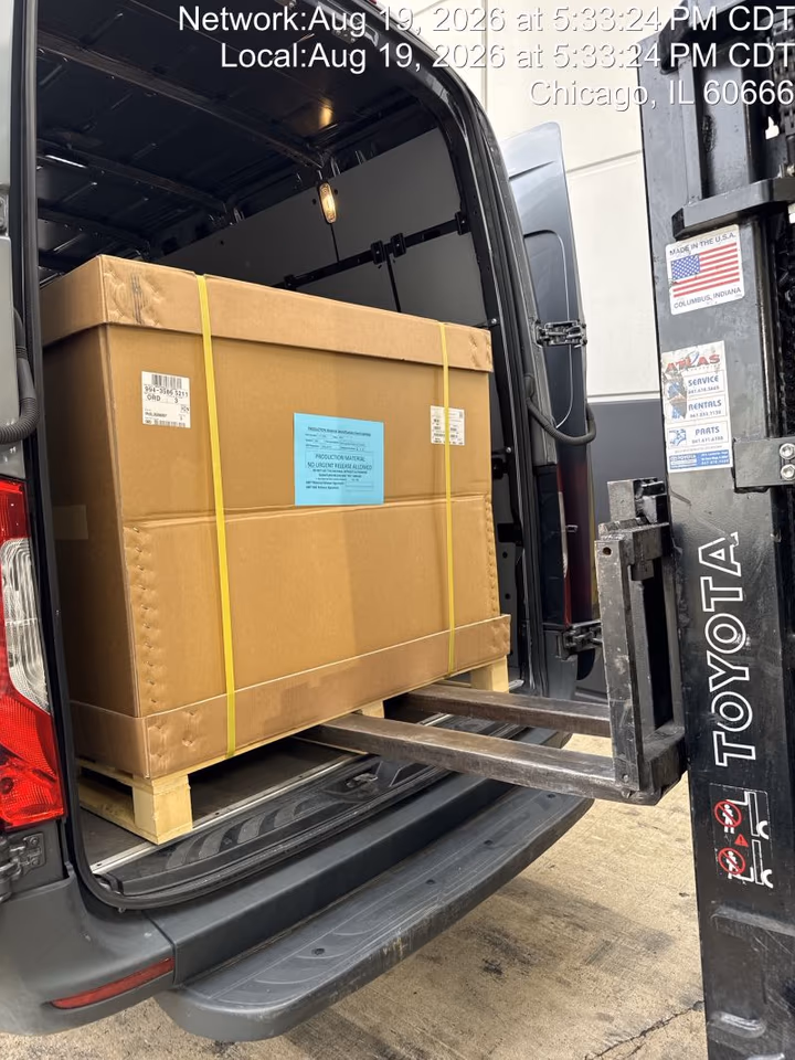 A forklift loading a strapped crate into the back of a BEExpedite Sprinter at an O’Hare cargo dock